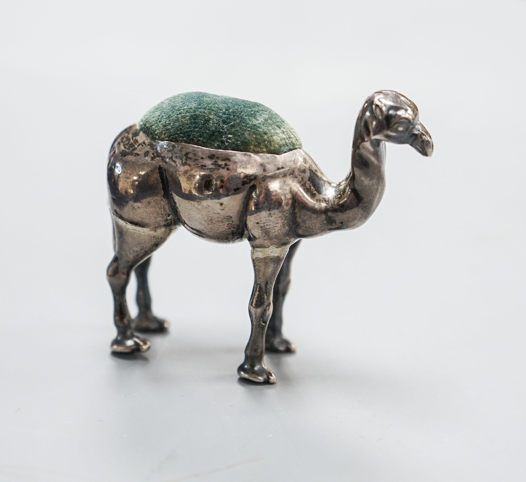 A George V novelty silver mounted pin cushion, modelled as a camel, ?H &S, Birmingham, 1911, height 49mm(a.f).